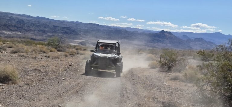 RZR off-road vehicle on a dusty Nevada desert trail near Las Vegas, with rugged mountains and blue sky—perfect for ATV tours.