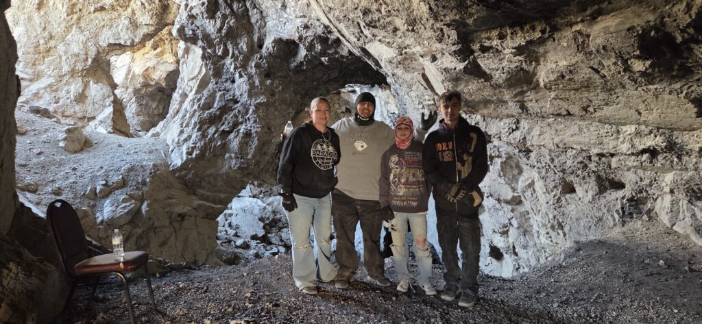 Group in casual wear stands inside a Nevada cave near Las Vegas, sunlight pouring in—perfect for ATV tours or RZR off-road adventures.