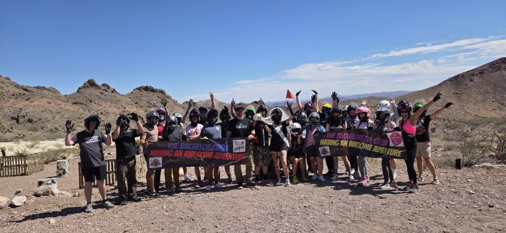 Group in helmets poses with “THE BACHELORETTE” banners on a Nevada desert ATV tour near Las Vegas and the Colorado River.