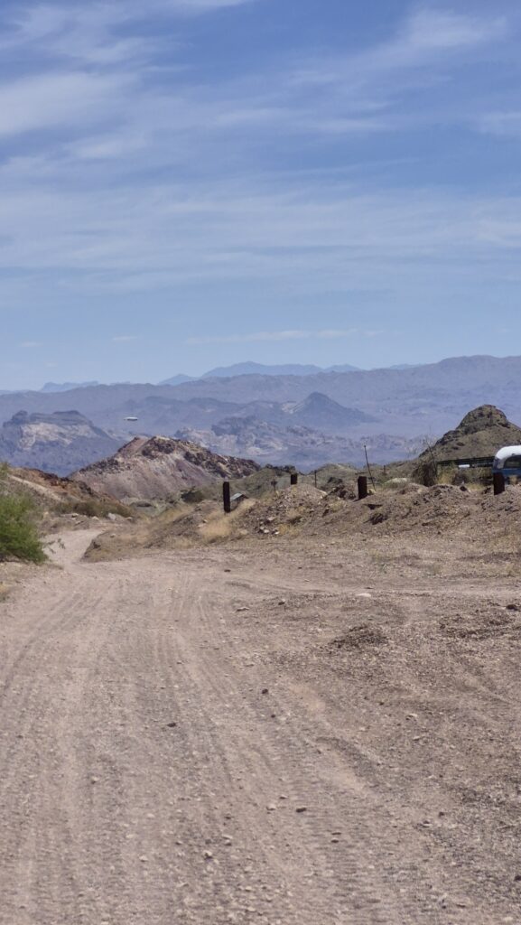 A dusty dirt road near Las Vegas winds through the Nevada desert, perfect for ATV tours or RZR rides with mountain views.