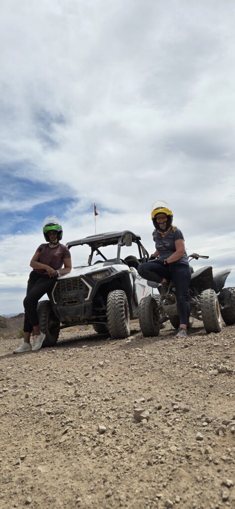 Adventure seekers in yellow helmets on an ATV tour near Las Vegas, Nevada, posing with off-road vehicles on a rocky desert trail.