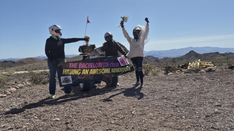 Bachelorette crew in helmets, bridal veil, and bouquet by ATV in Nevada desert near Las Vegas on RZR off-road adventure tour.