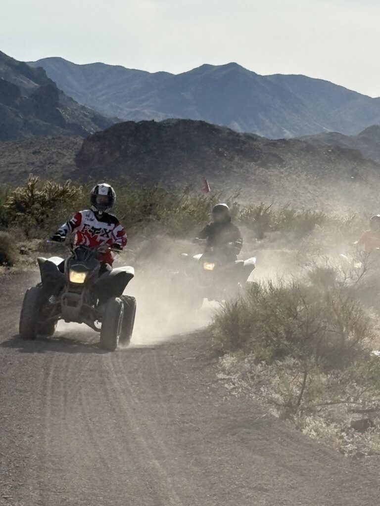 ATV riders on a dusty Nevada desert trail near Las Vegas, surrounded by rocky hills—perfect for guided ATV tours and adventure.