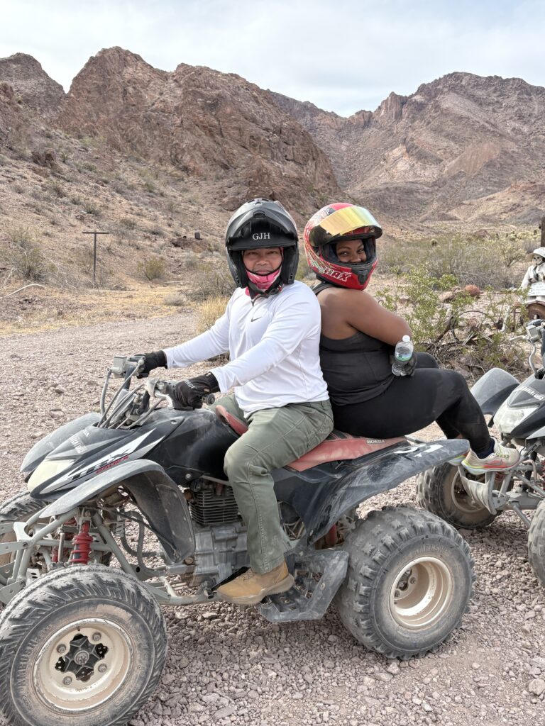 Two people in helmets ride an ATV near Las Vegas, Nevada, surrounded by rocky desert and brown mountains on an exciting ATV tour.