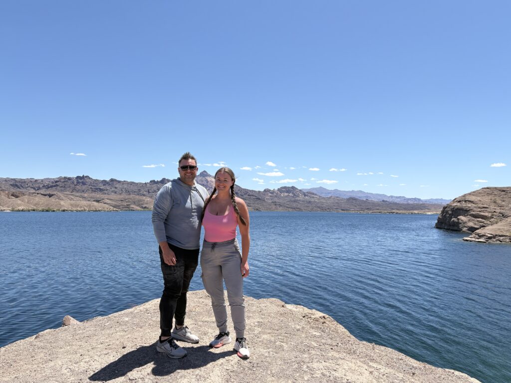 Couple smiles on a rocky ledge by the blue Colorado River near Las Vegas, Nevada, ready for outdoor ATV and RZR adventures.