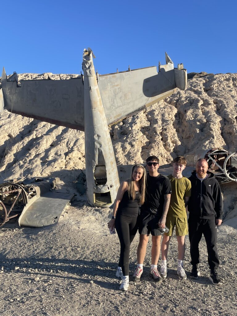 Smiling group by an old airplane wreck in Nevada desert during an ATV tour near Las Vegas and the Colorado River.