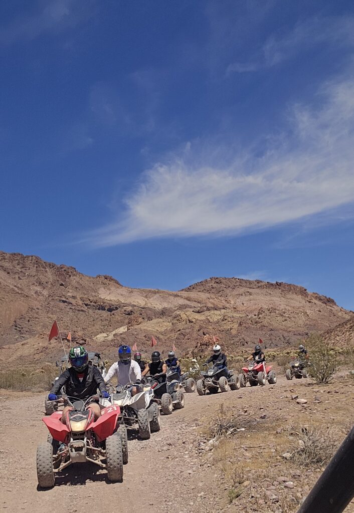 Six riders on ATVs explore a rocky Nevada desert trail near Las Vegas under blue skies, perfect for ATV tours and off-road adventures.