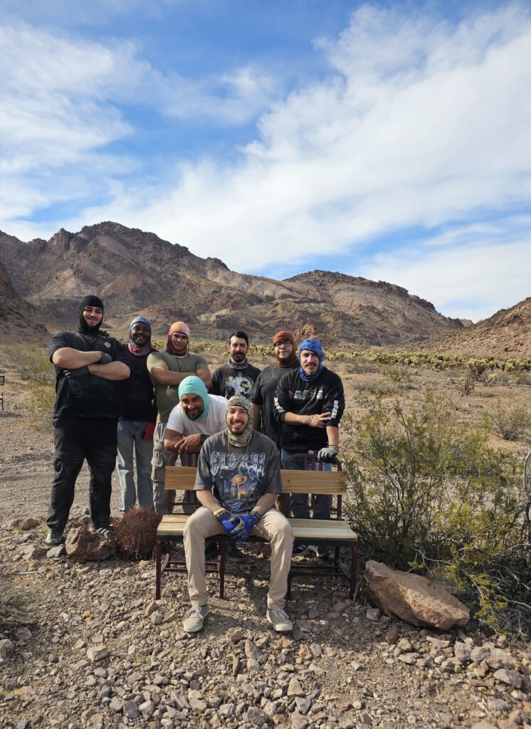 Group photo in Nevada desert near Las Vegas mountains, posing after ATV tour; all in casual wear and beanies.