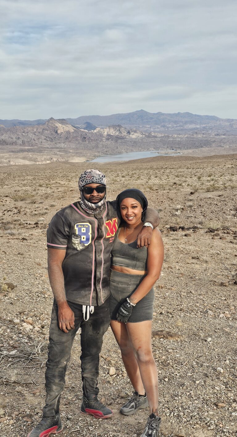 Smiling couple in Nevada’s rocky desert near the Colorado River, ready for ATV tours by Las Vegas mountains.