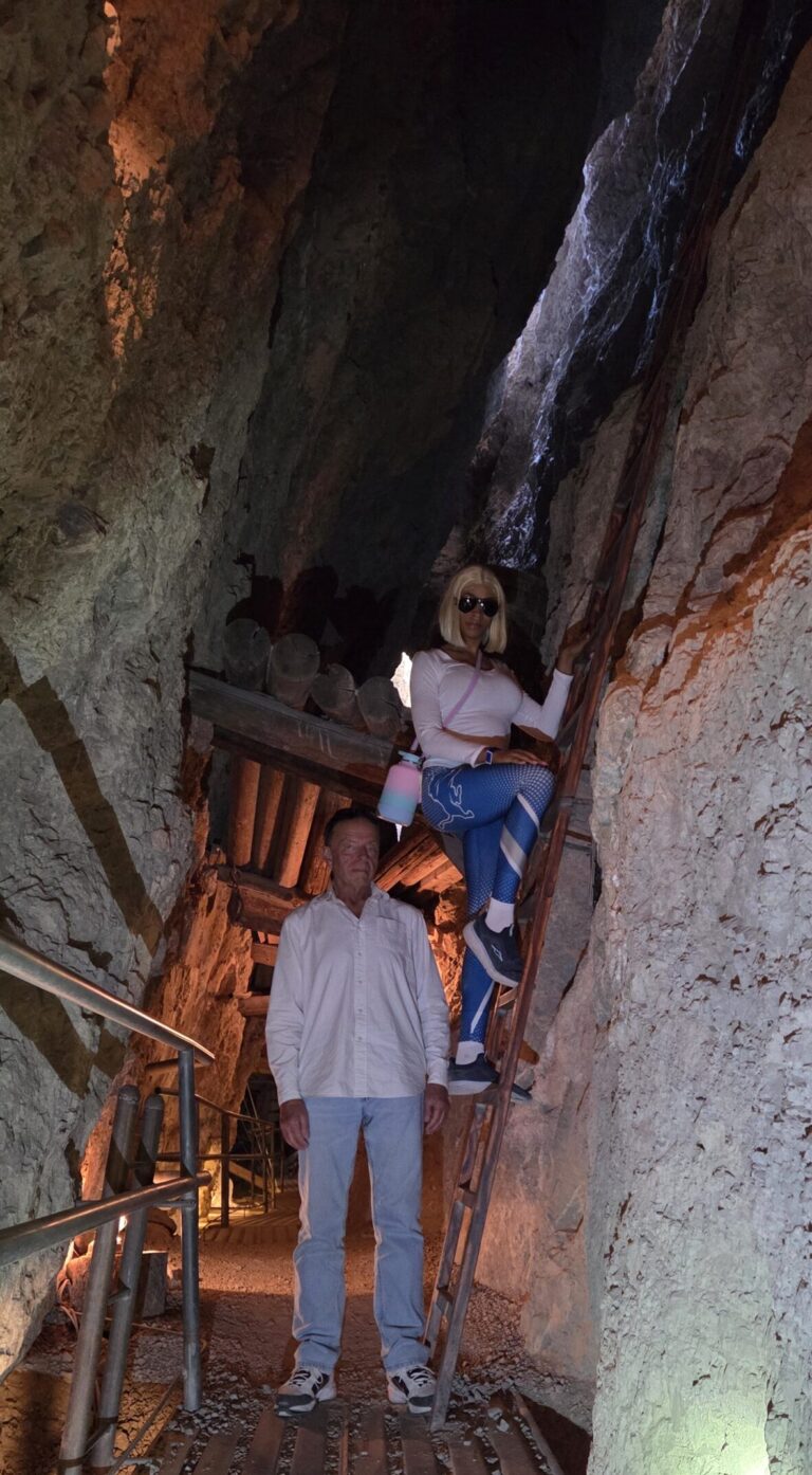 Exploring a rocky Nevada cave near Las Vegas: man on walkway, woman climbs ladder. Great for ATV tours and adventure seekers.