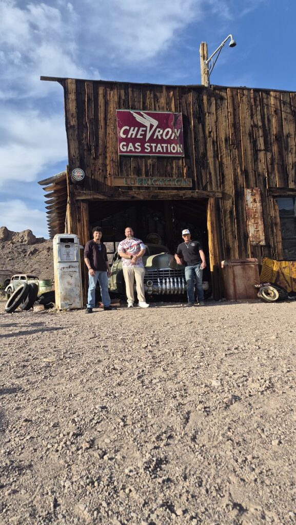 Three men at a rustic gas station near Las Vegas, Nevada, perfect for Ghost Town sightseeing and Colorado River adventures.