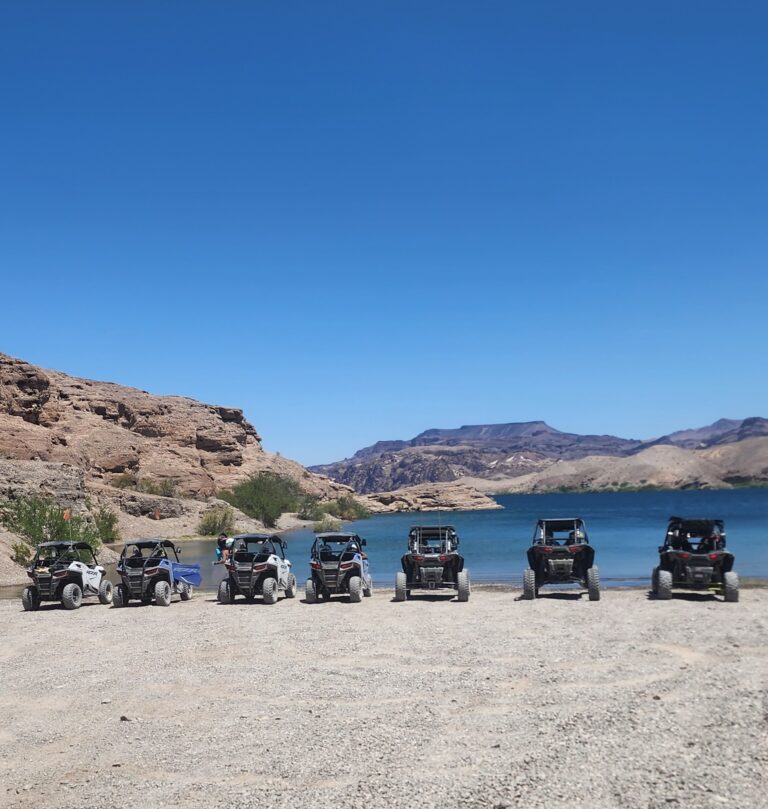 ATV and RZR off-road vehicles lined up near the Colorado River, Nevada desert hills, perfect for Las Vegas ghost town tours.