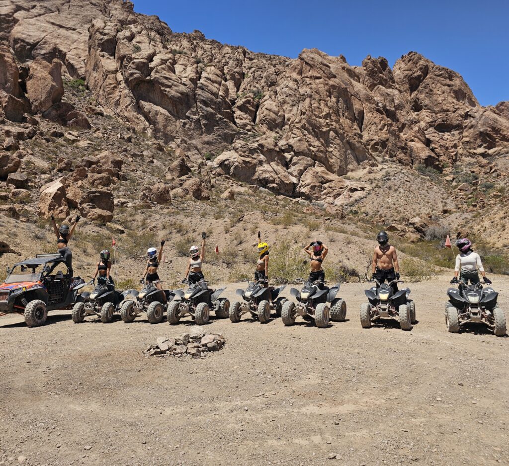 Adventurers in helmets on ATVs line up in Nevada desert for a Las Vegas ATV tour near stunning rock formations and RZR rides.