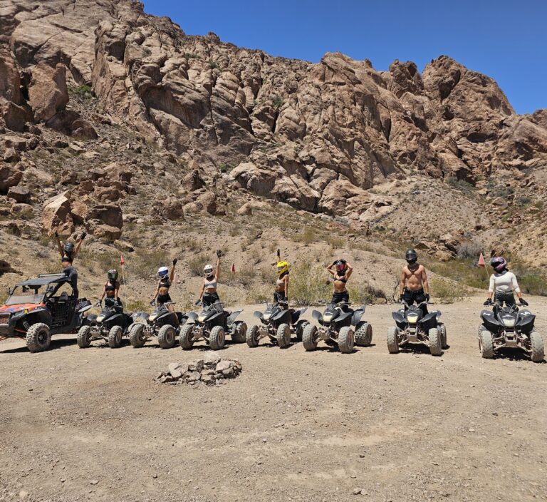 Adventurers in helmets on ATVs line up in Nevada desert for a Las Vegas ATV tour near stunning rock formations and RZR rides.