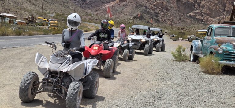 Adventurers on ATVs and a utility vehicle tour a Nevada desert near Las Vegas, exploring rocky hills and Ghost Town relics.