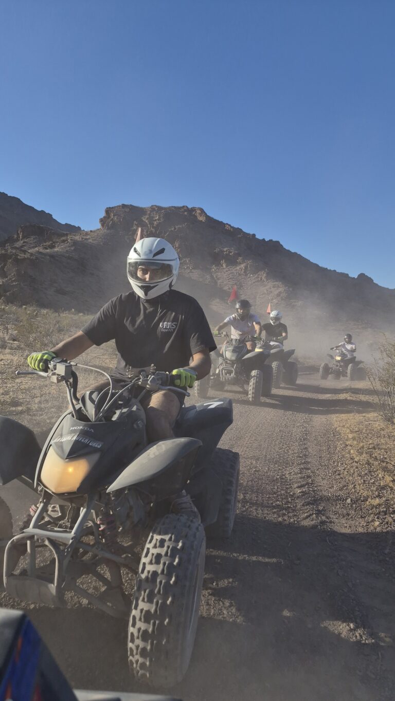 Adventurers on an ATV tour near Las Vegas ride dusty desert trails with mountain views under blue Nevada skies.
