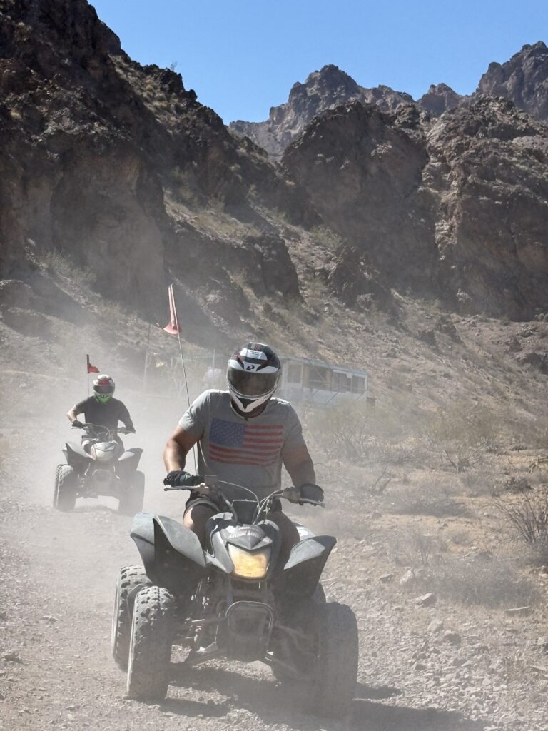 Two riders on ATVs explore a rugged Nevada desert trail near Las Vegas, enjoying an exciting ATV tour under clear blue skies.