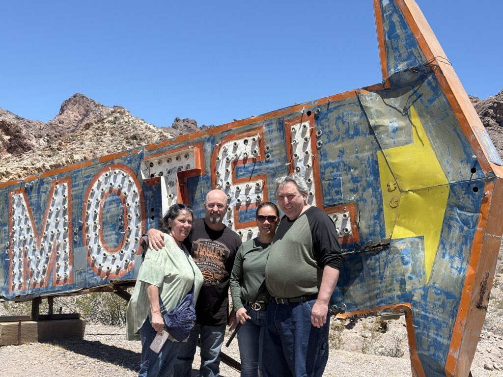 Smiling group by vintage MOTEL sign in Nevada desert near Las Vegas, perfect for ATV tours and ghost town sightseeing.