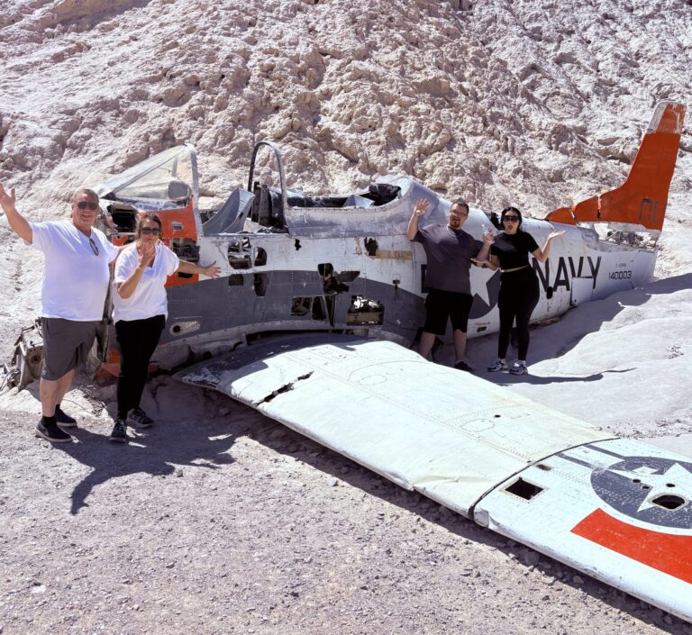 Smiling group at Navy aircraft wreck in Nevada’s rocky desert, near Las Vegas—perfect for ATV tours and Ghost Town sightseeing.