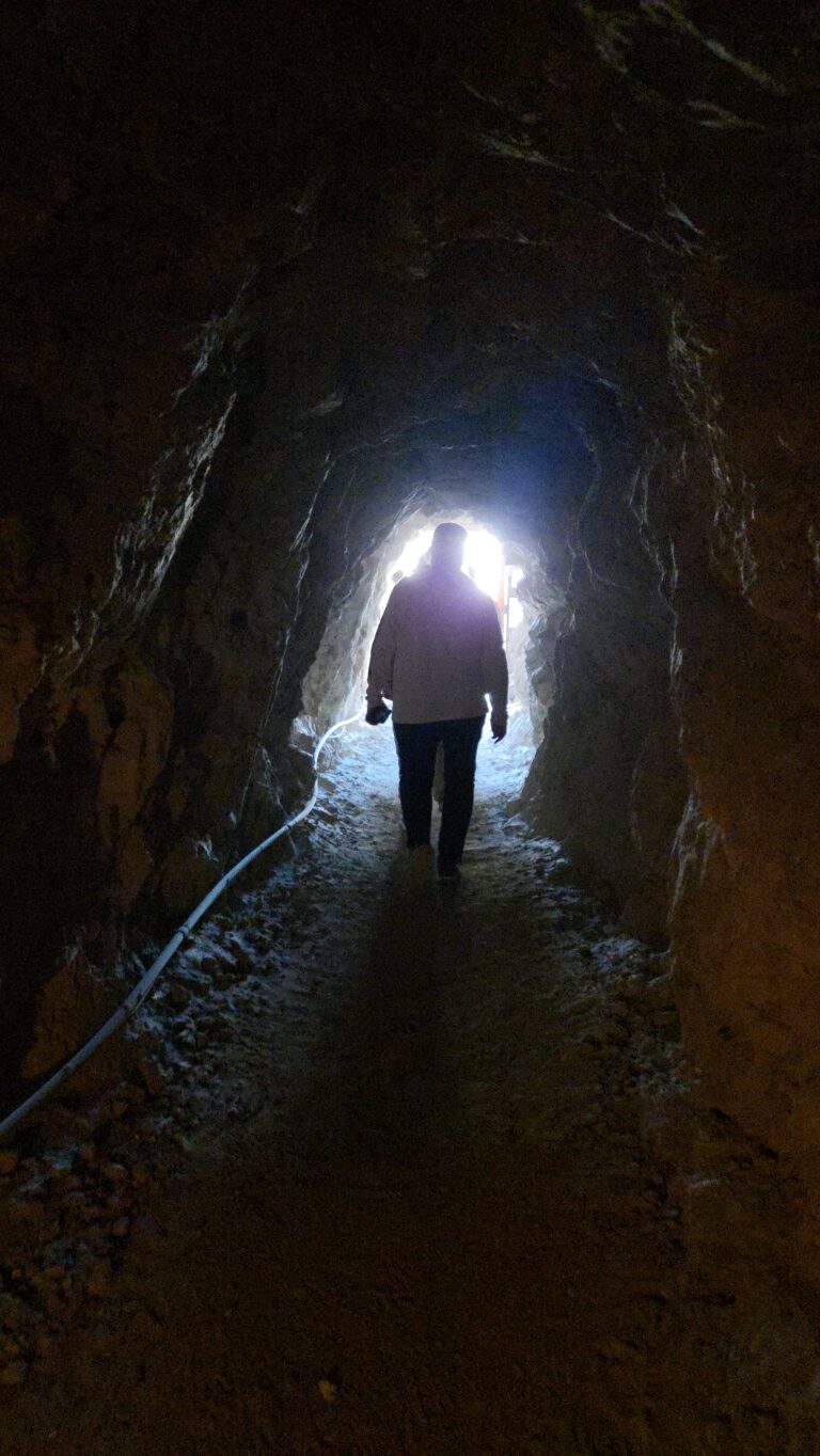 Silhouette of a person in a dim Nevada tunnel near Las Vegas, bright exit ahead; ideal for ATV tours or Colorado River adventures.