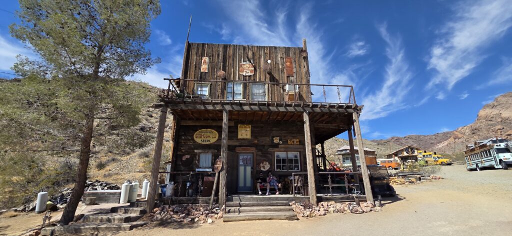 Rustic two-story building in Nevada ghost town near Las Vegas; porch seating, old signs, desert backdrop; ideal for ATV tours.