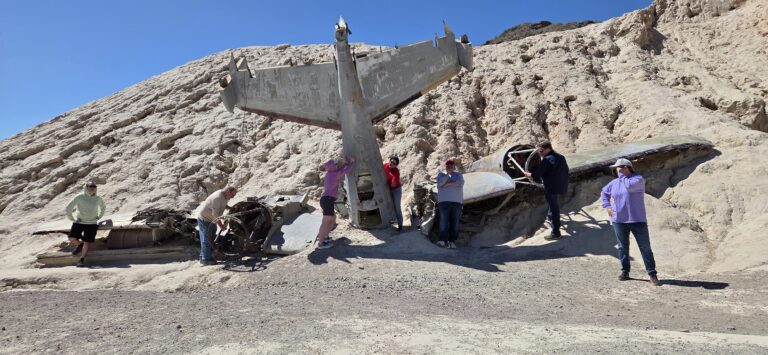 Group explores old airplane wreckage on a Nevada hillside near Las Vegas, perfect for ATV tours or Ghost Town sightseeing.