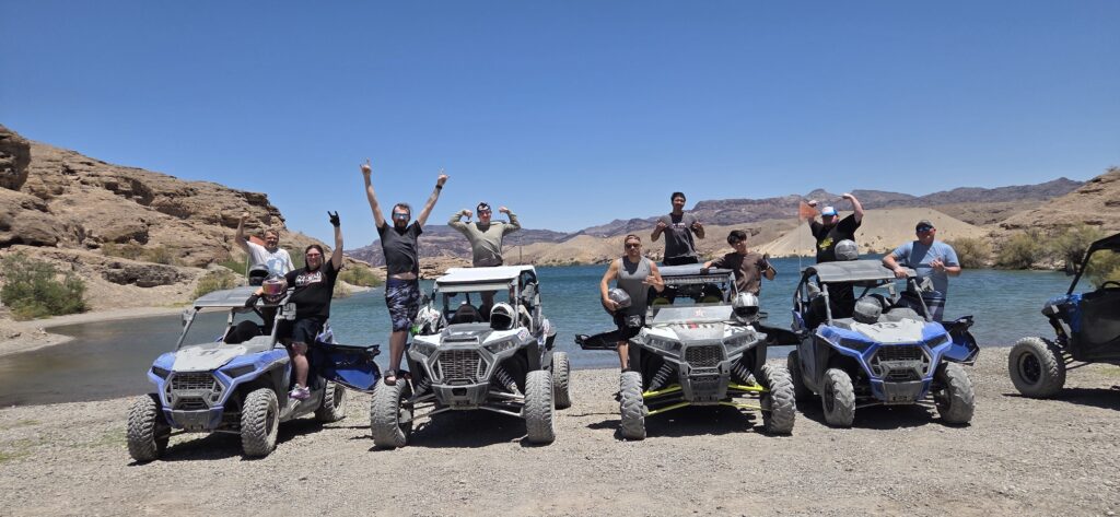 Adventurers enjoy an ATV tour by the Colorado River near Las Vegas, Nevada, with RZR rides and rocky hills under a blue sky.