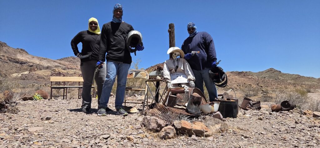 Tourists in sun hats pose by a cowboy skeleton at a Nevada desert ghost town near Las Vegas, perfect for ATV or RZR tours.