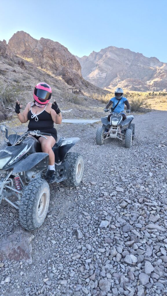 Two riders on ATVs explore a rocky Nevada desert trail near Las Vegas, with mountains in the background on an ATV tour adventure.
