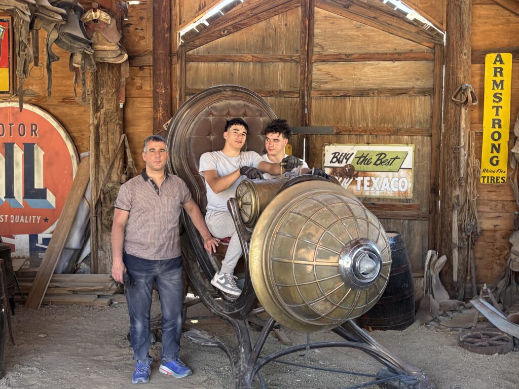 Family poses in a Nevada ghost town; teens ride vintage rocket near antique signs. Great for Las Vegas Ghost Town sightseeing tours.