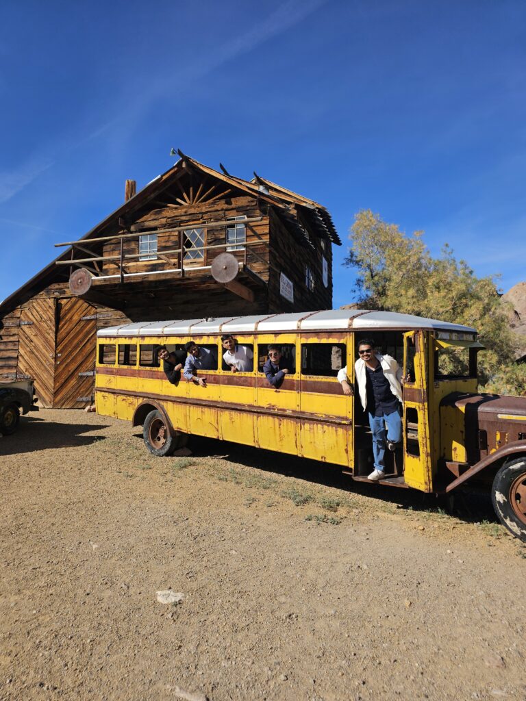 Smiling group in vintage yellow bus at Nelson Ghost Town near Las Vegas, Nevada—perfect for ghost town sightseeing adventures.