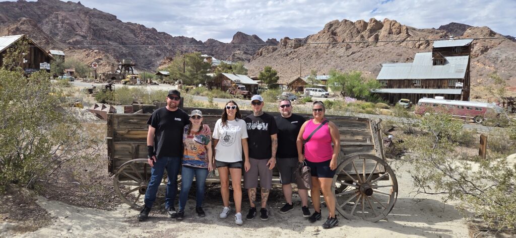 Group by a vintage wagon in Nelson Ghost Town, Nevada—perfect spot for Las Vegas ghost town sightseeing near the Colorado River.