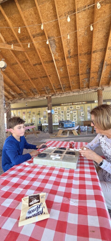 Family enjoys a lively board game night in Las Vegas, Nevada, with snacks and framed photos after a day of Ghost Town sightseeing.