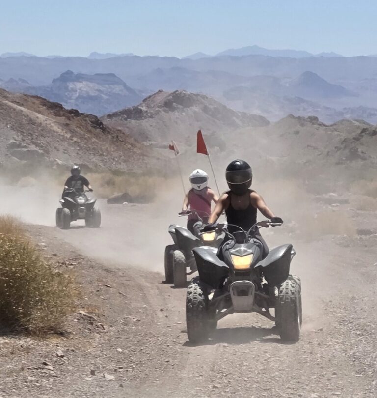 ATV tour near Las Vegas: three riders explore dusty desert trails with mountain views under a clear Nevada sky.