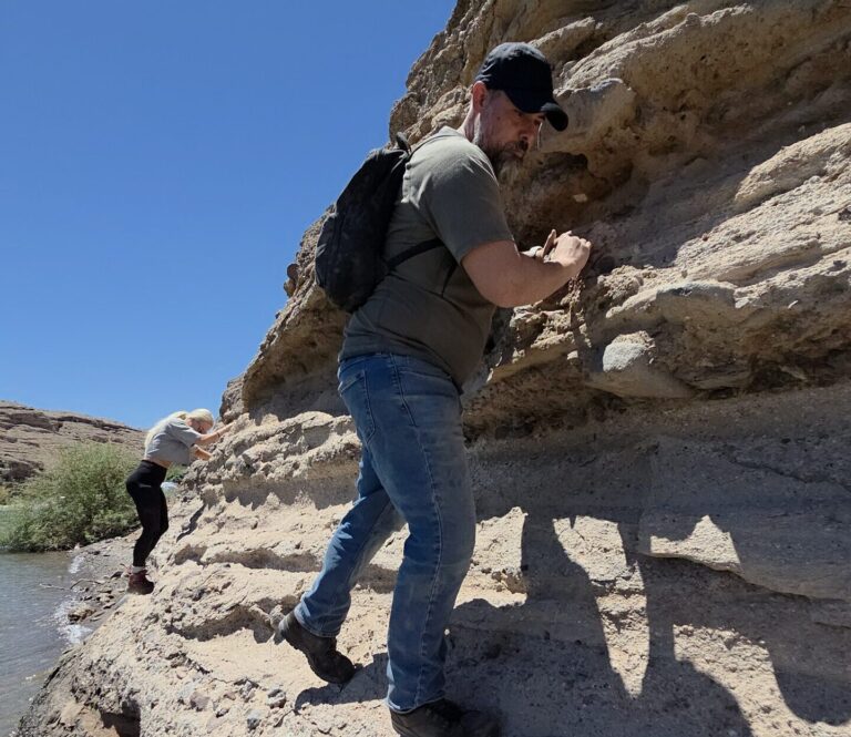 Adventurers climb layered Nevada rocks by a clear stream near Las Vegas; ideal for ATV or RZR tours along the Colorado River.