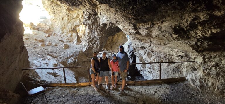 Group inside a Nevada cave near Las Vegas, standing by a railing with sunlight at the entrance—perfect for Colorado River ATV tours.
