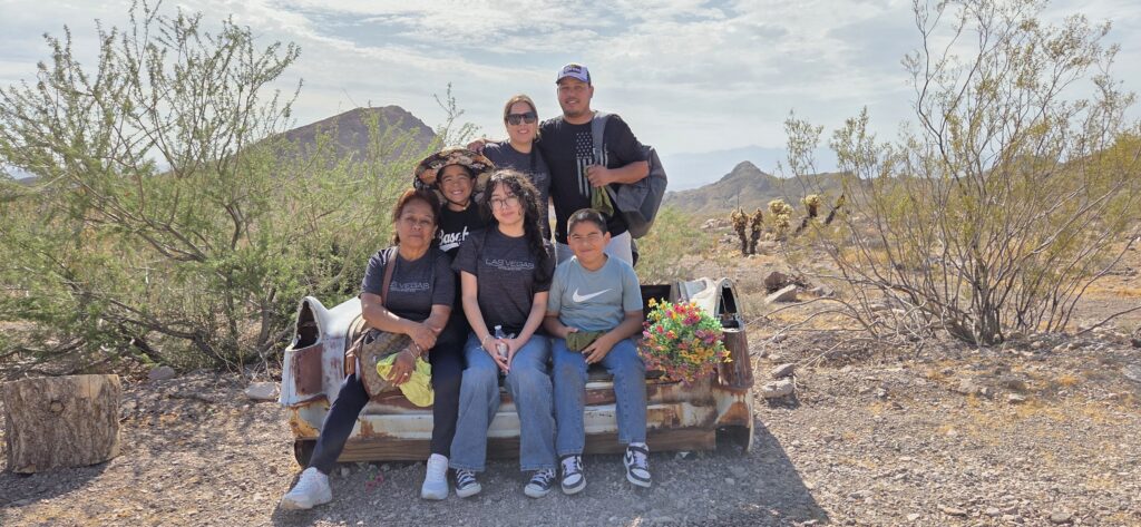Group relaxing by an old car seat in the Nevada desert near Las Vegas, mountains and bushes behind—perfect for ATV tours and adventure.
