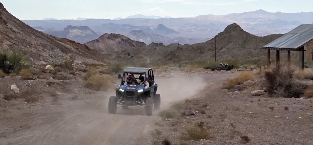 ATV drives on a dusty Nevada desert trail near Las Vegas, with mountains, shelter, perfect for RZR off-road tours and Ghost Town trips.