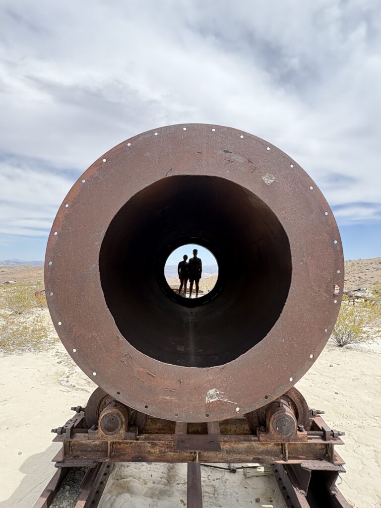 Two people at the end of a rusty pipe on rails in Nevada's desert, near Las Vegas—ideal for ATV tours and off-road adventures.