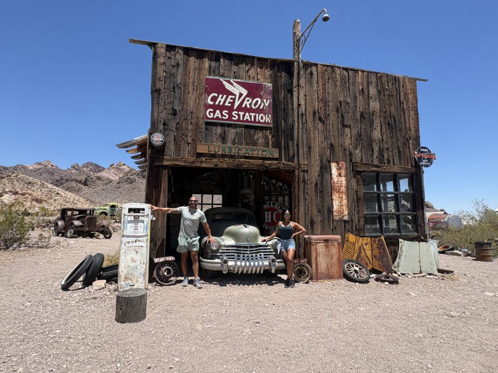 Adventurers pose by a vintage green car at a historic Las Vegas gas station, perfect for Nevada ghost town sightseeing.