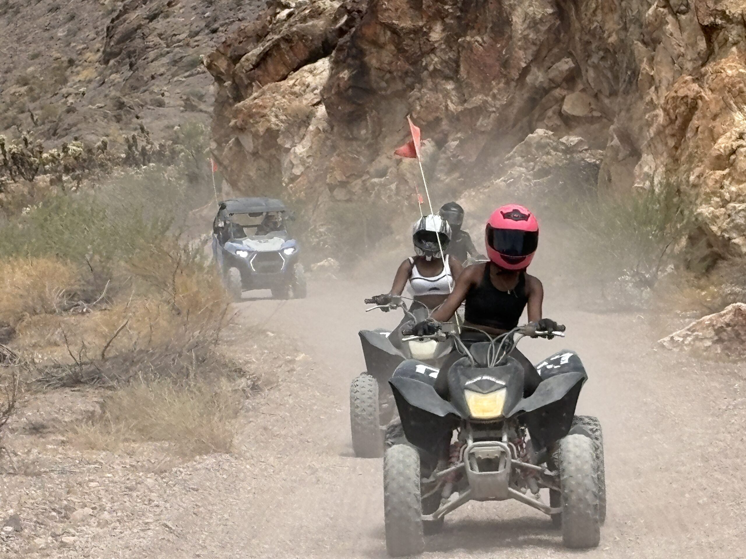 Riders on ATVs and a side-by-side explore a dusty Nevada desert trail near Las Vegas, perfect for thrilling ATV tours and RZR adventures.