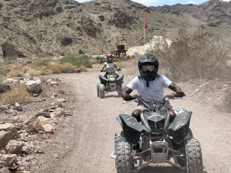 ATV riders explore a dusty Nevada desert trail near Las Vegas, with rocky hills and mountains—perfect for RZR off-road tours.