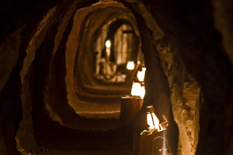 Explore a dimly lit Nevada tunnel with rocky walls, lanterns aglow—perfect for Las Vegas ATV tours or Colorado River sightseeing.