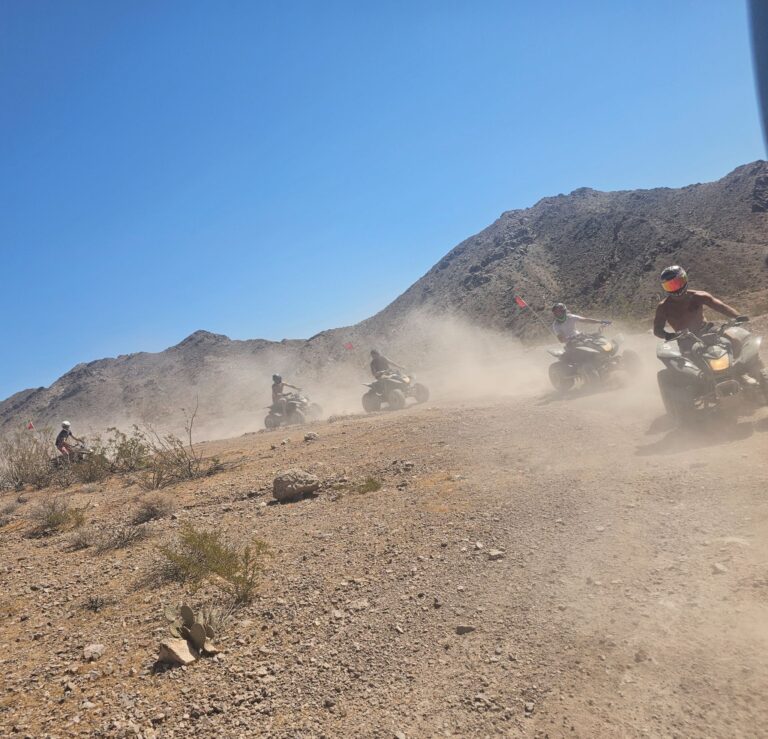 Group riding ATVs on a dusty Nevada desert trail near Las Vegas, with mountain views and dust clouds on an exciting ATV tour.