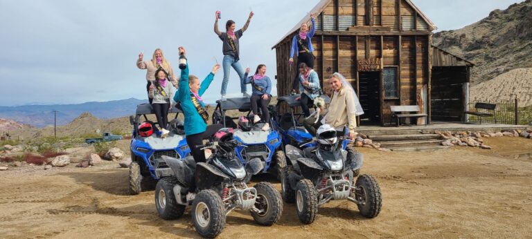 Excited group on blue ATVs and UTVs at a Nevada desert ghost town near Las Vegas, ready for an ATV tour adventure.