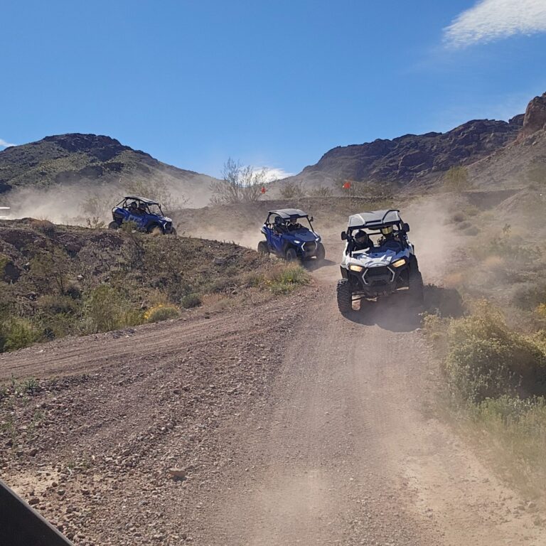 Blue off-road vehicles on a dusty Nevada desert trail near Las Vegas, ideal for RZR ATV tours and Colorado River adventures.